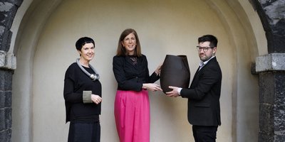 three people standing in an archway holding a sculpture