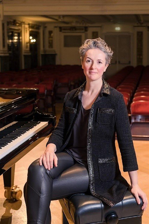 Portrait of Elaine Loebenstein sitting at her piano
