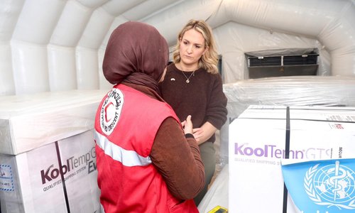 Minister McEntee with Red Crescent worker in aid tent. Boxes of aid in background.