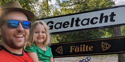 dad and his daughter in front of a Gaeltacht sign
