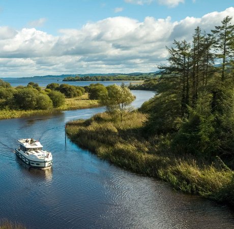 image taken from above of a boat travelling along Scariff River in County Clare, with blue skies and fluffy white clouds