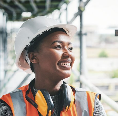 A construction site worker wearing a hard hat and carrying a walkie talkie.