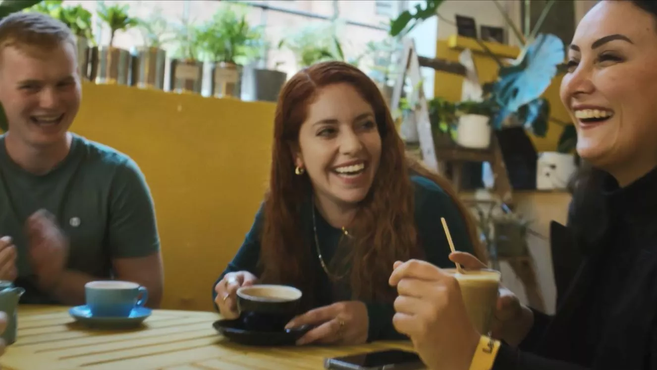 three people laughing over coffee