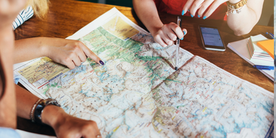 Three sets of hands pointing at a map to plan a journey
