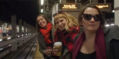 three women waiting for a train at the side of the track